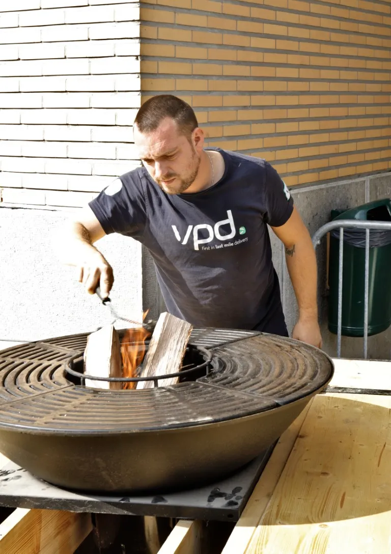 Iemand steekt het vuur op de barbecue aan op de jaarmarkt van Rode